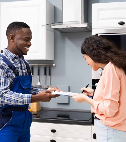 Smiling Customer Woman Signing Appliance Repair Invoice In Front Of Employee